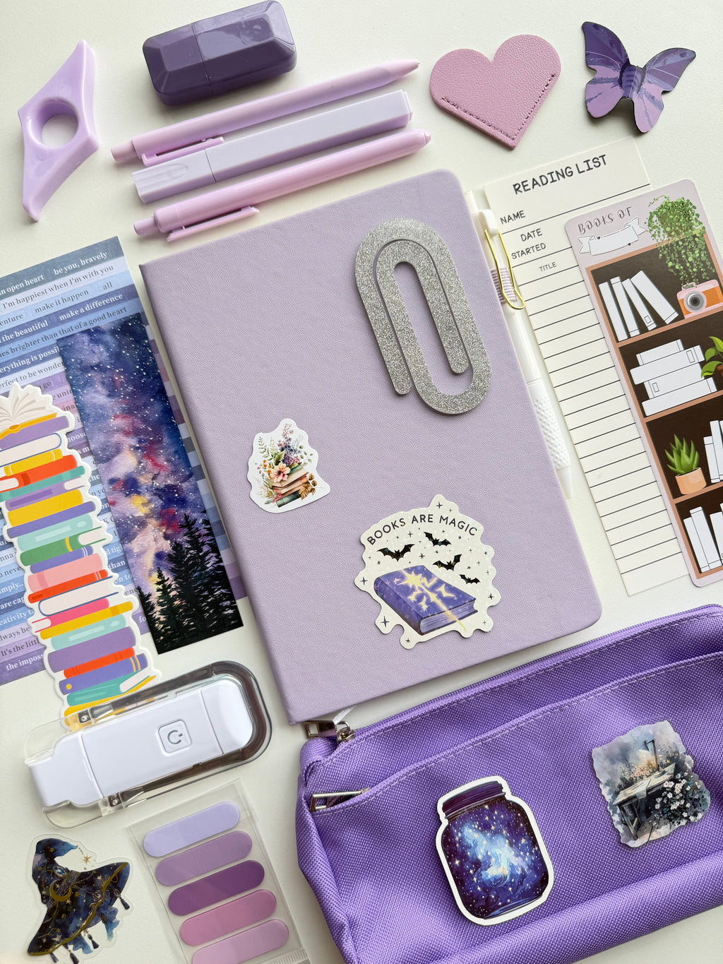 Purple stationery items including a notebook, pens, and stickers on a white background