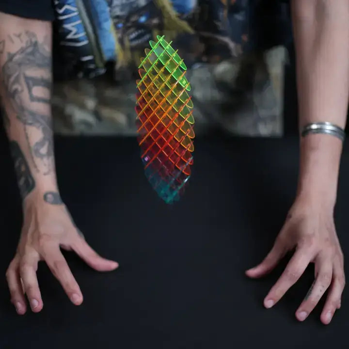 Colorful geometric object held between two hands on a dark surface