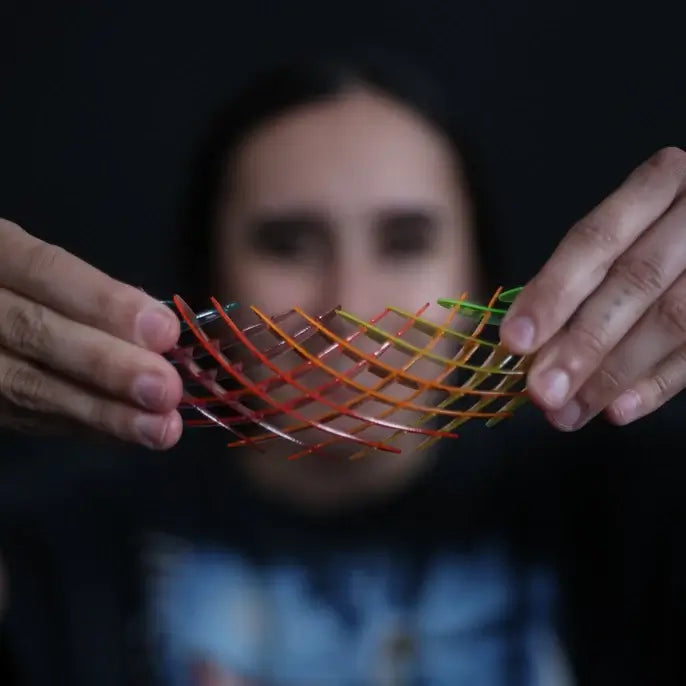 Person holding a colorful, wavy metal object against a dark background