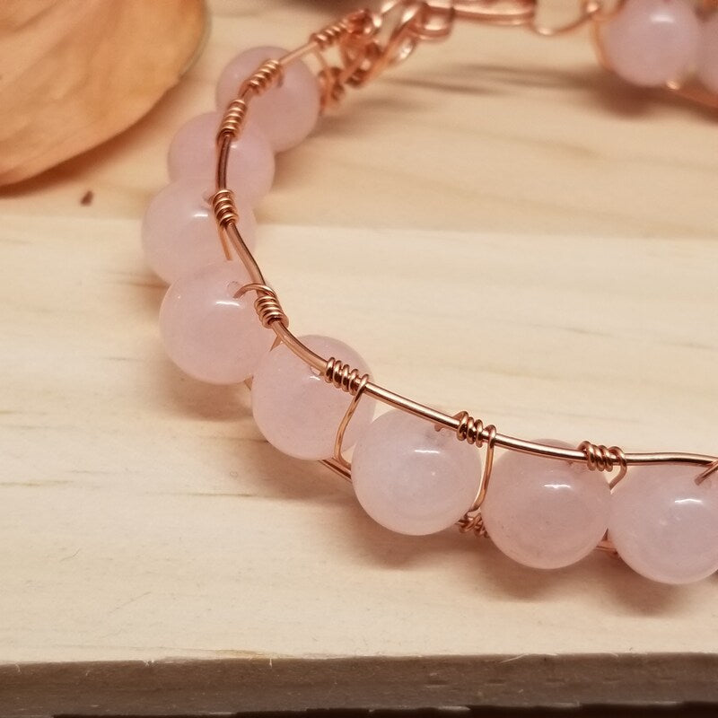 Rose gold bracelet with pink beads on a wooden surface
