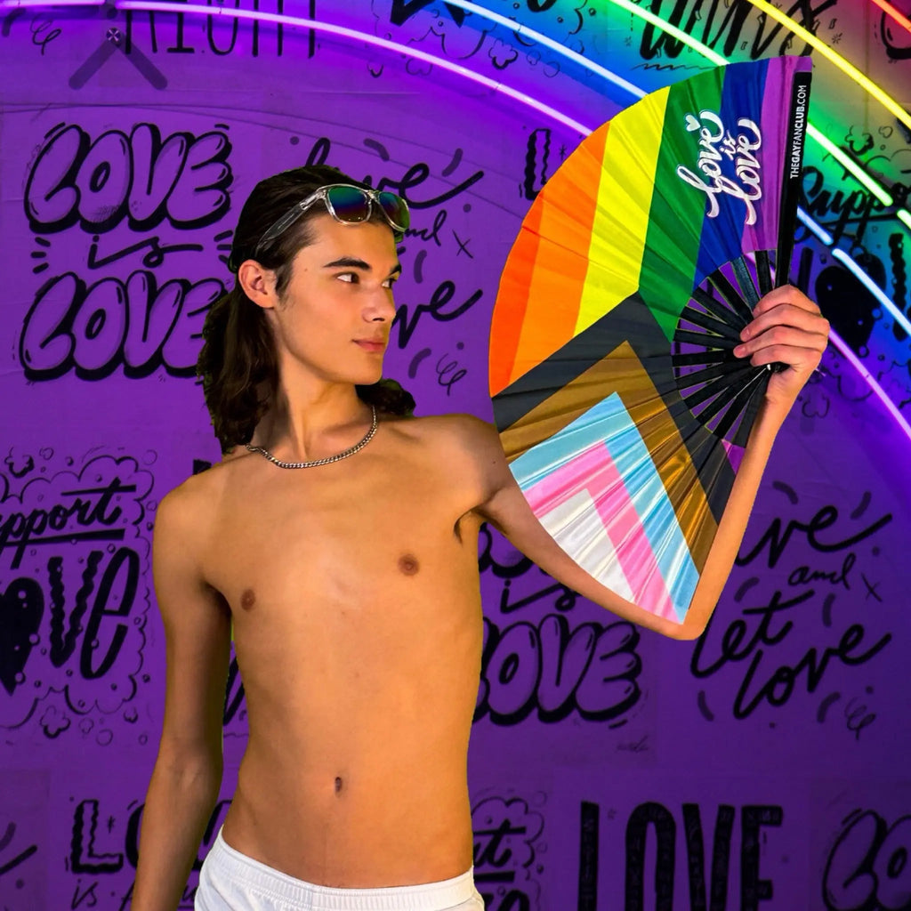 Person holding a rainbow-colored fan in front of a purple wall with 'love' text