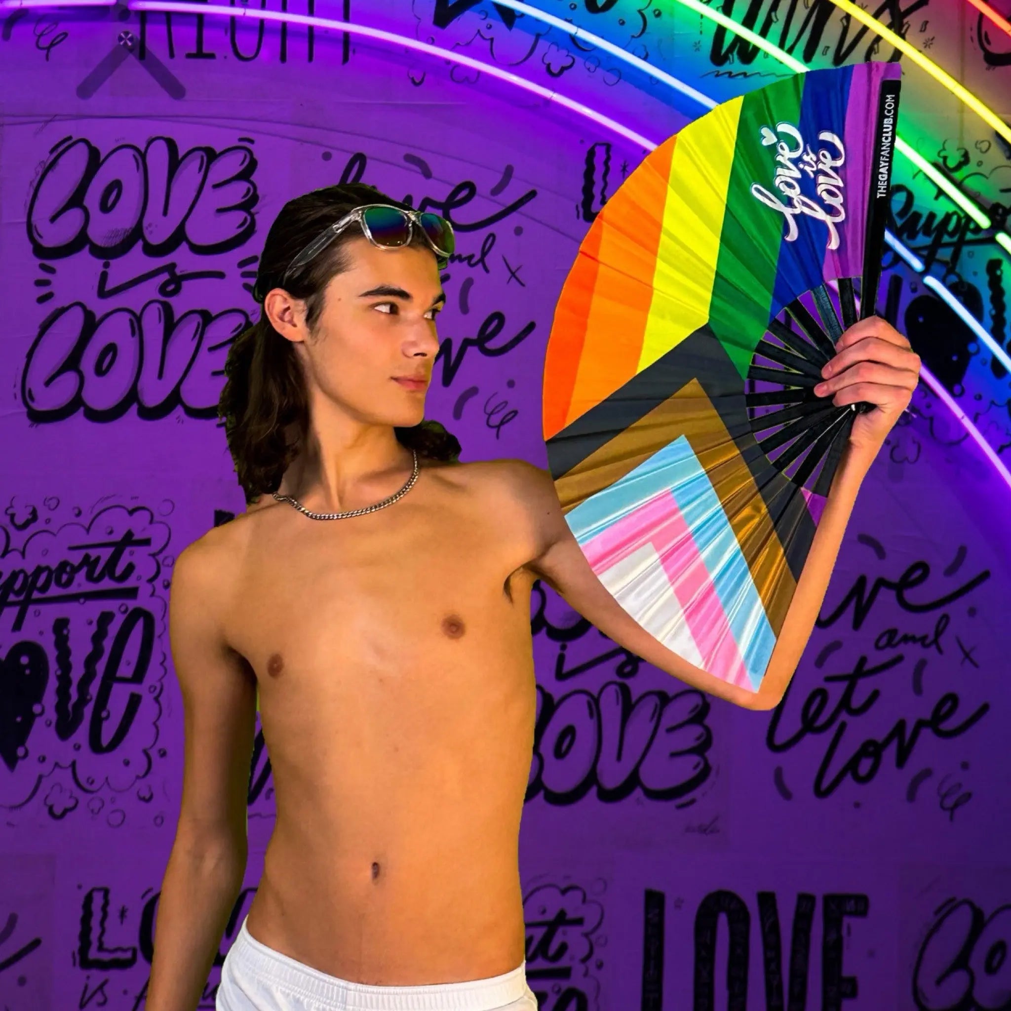 Person holding a rainbow-colored fan in front of a purple wall with 'love' text