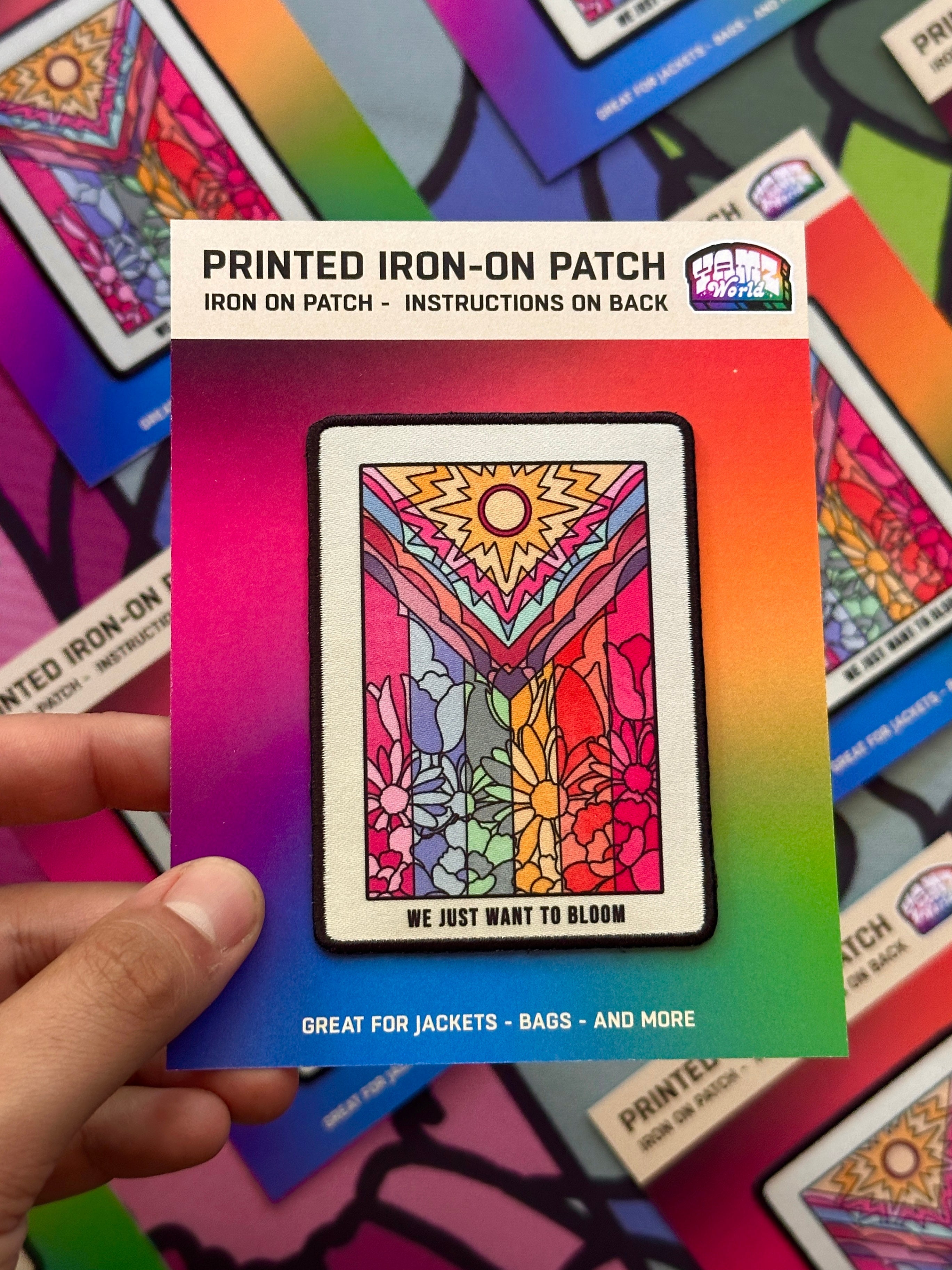 Colorful printed iron-on patch held by a hand with a multicolored background.
