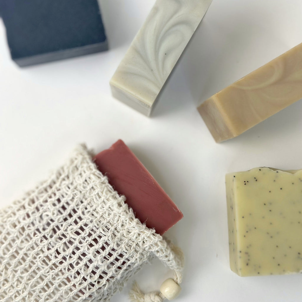 Various bars of soap and a mesh bag on a white surface