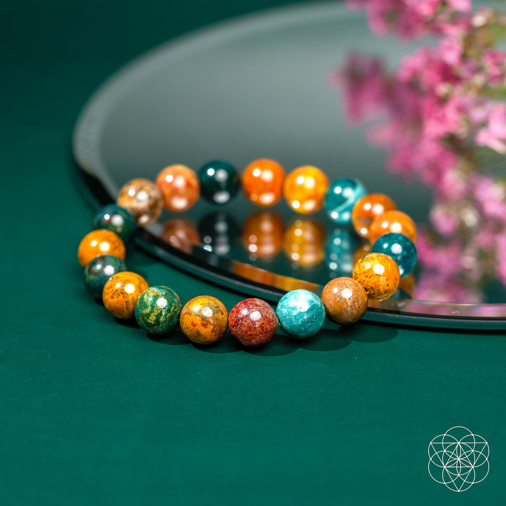 Colorful beaded bracelet on a reflective surface with a blurred floral background