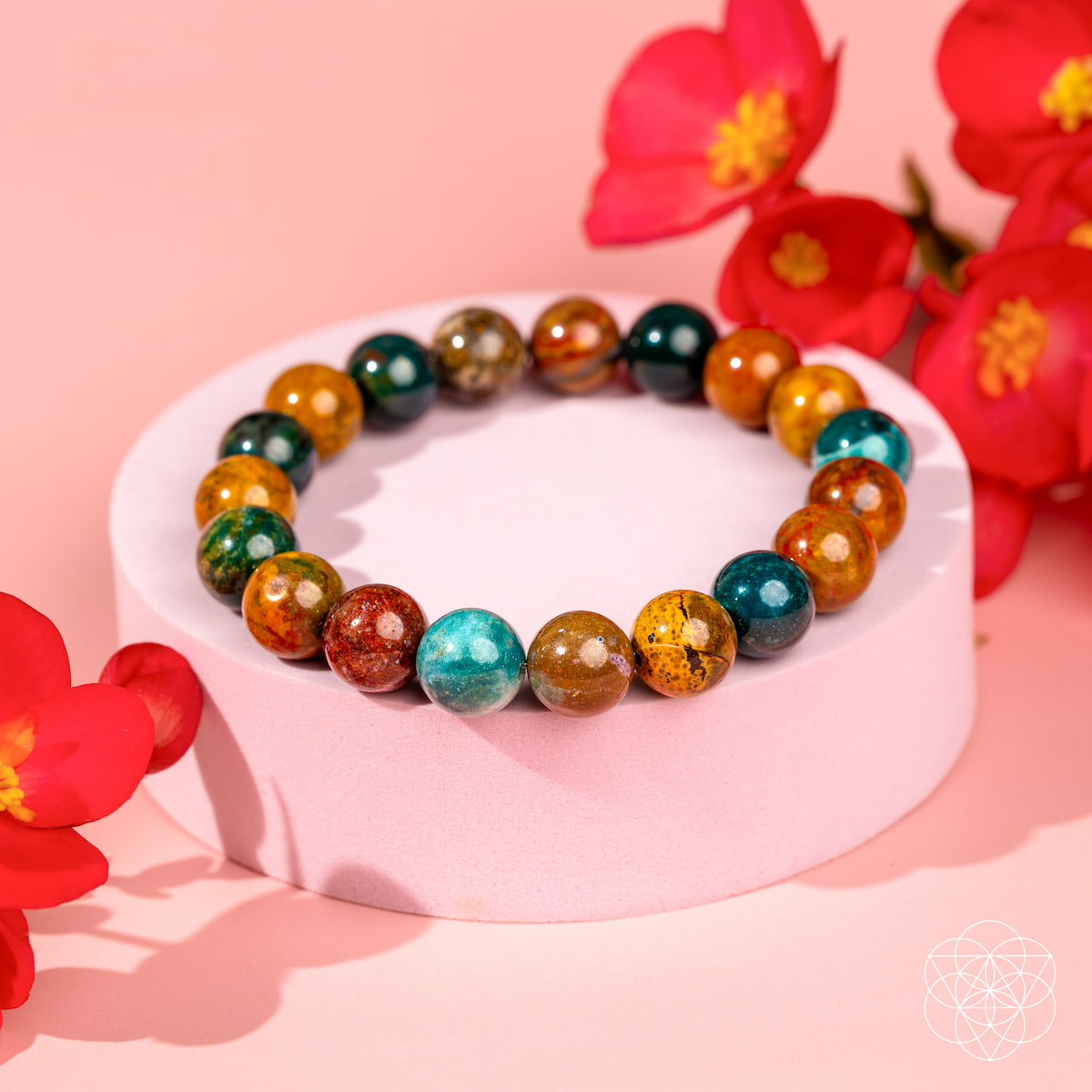 Multicolored beaded bracelet on a pink stand with red flowers in the background