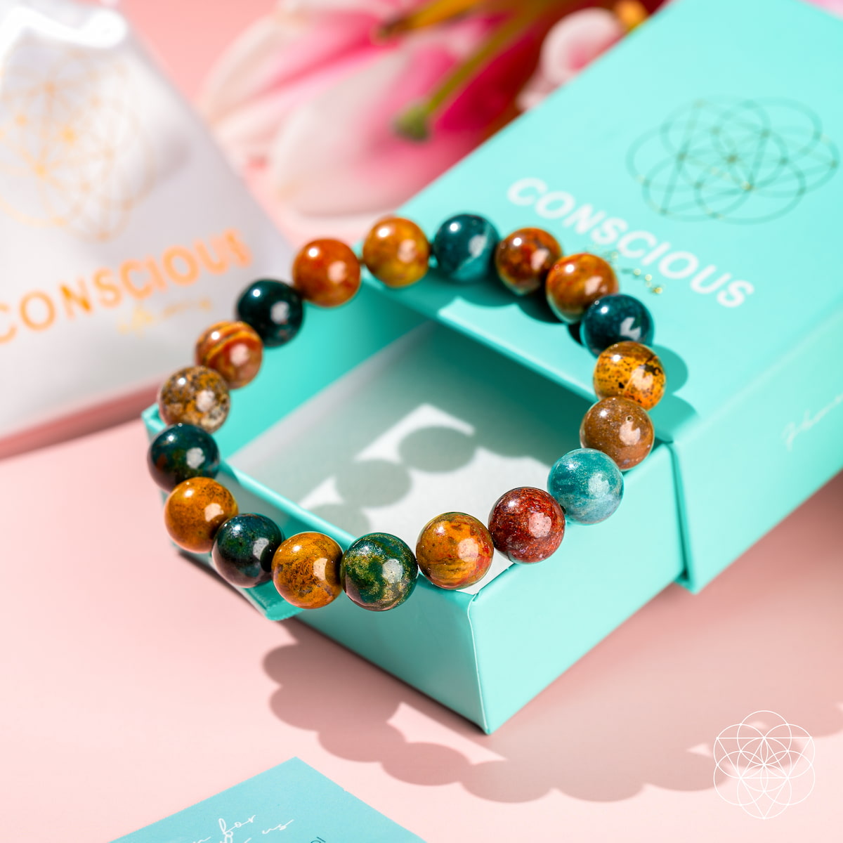 Multicolored beaded bracelet on a turquoise box with 'Conscious' branding.