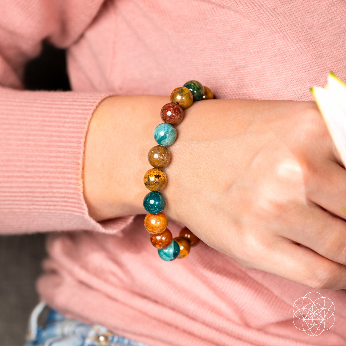 Colorful beaded bracelet on a wrist with a pink sleeve