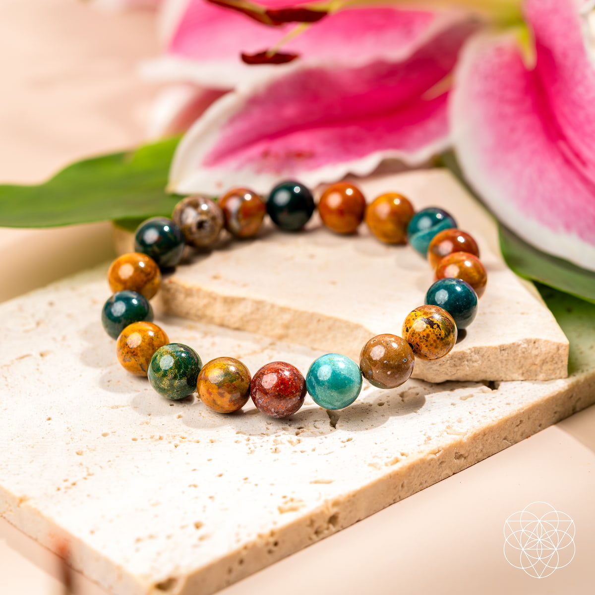 Multicolored beaded bracelet on a wooden surface with pink flowers in the background