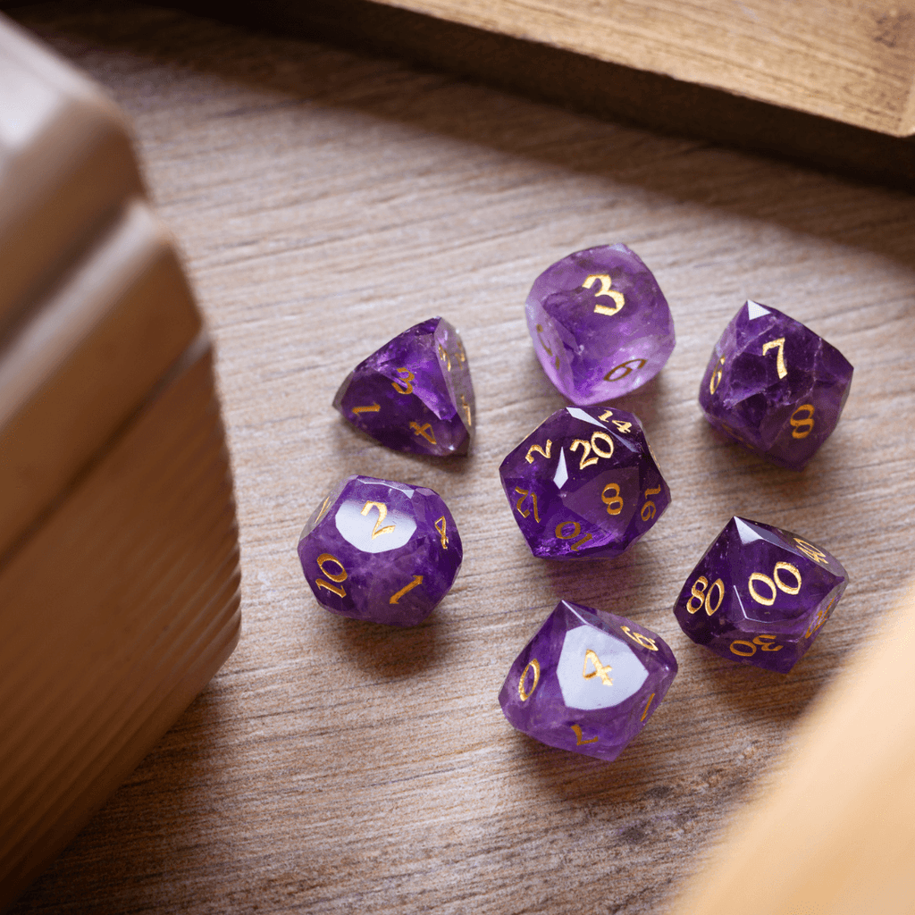 Purple polyhedral dice set with gold numbers on a wooden surface