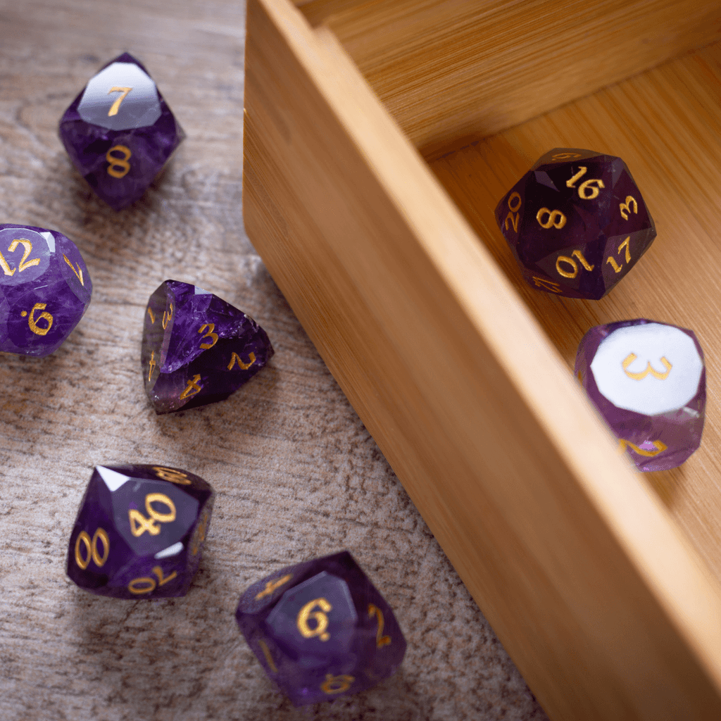 Purple polyhedral dice with gold numbers on a wooden surface