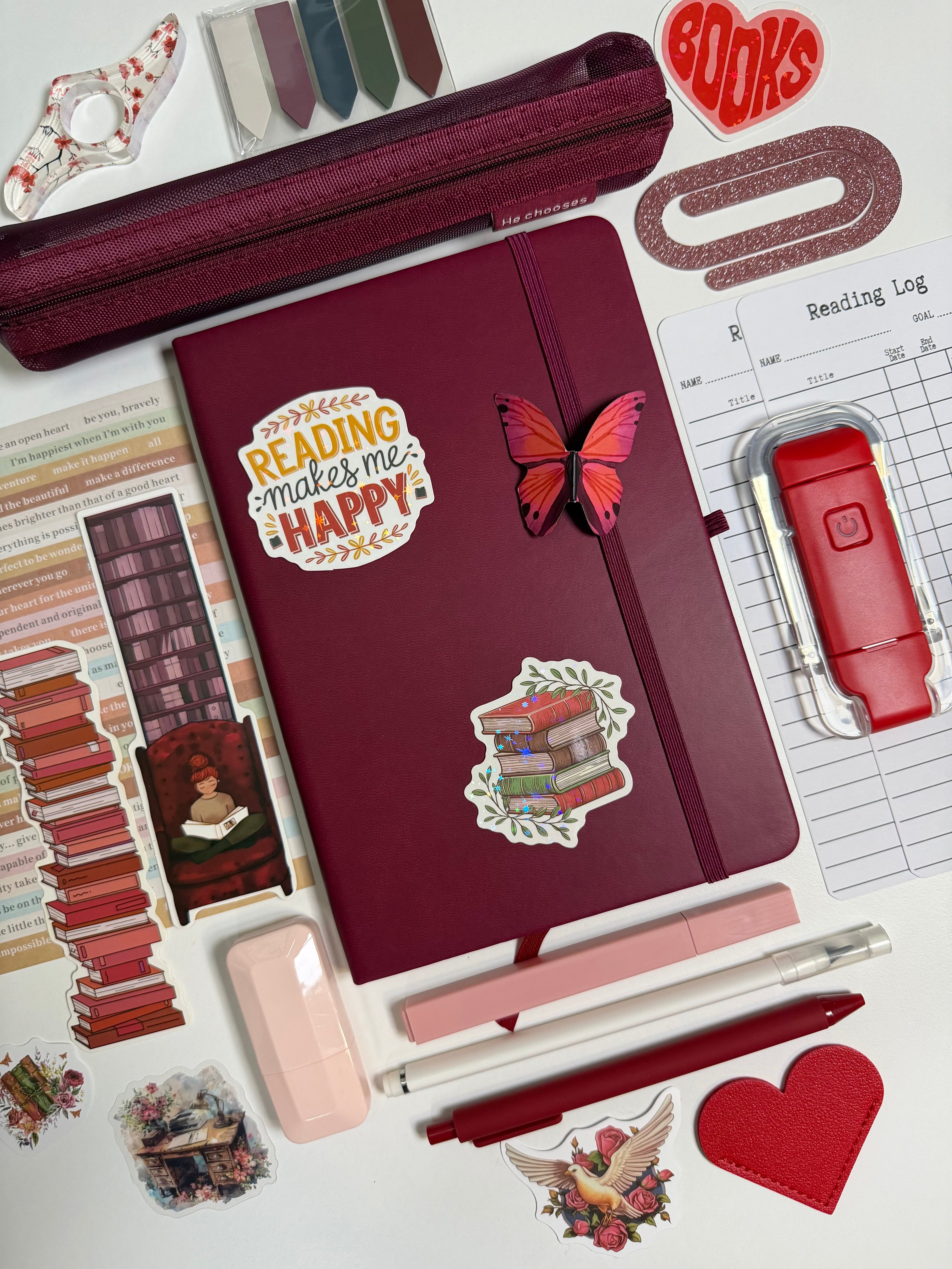 Maroon notebook with stickers on a white background with stationery items