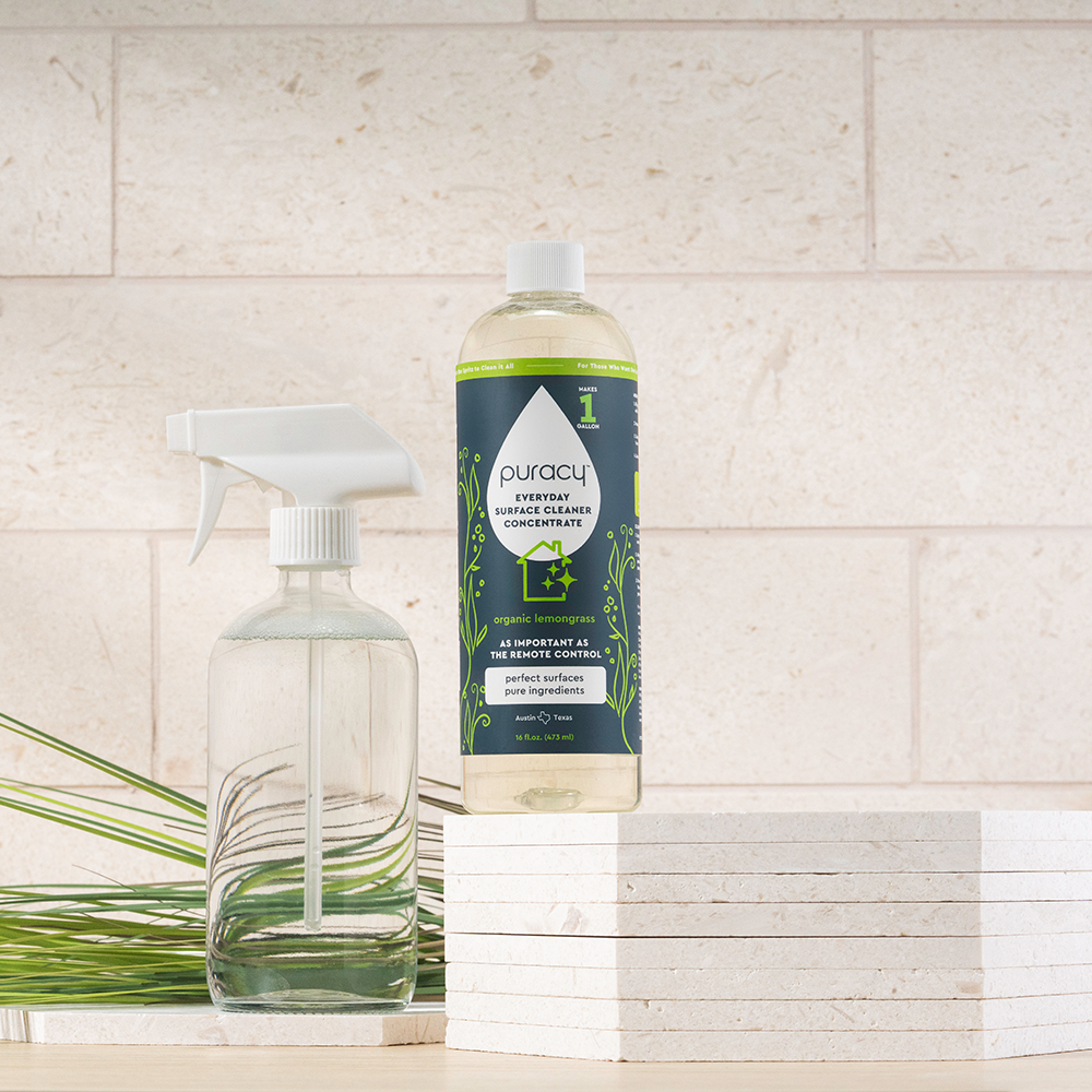 Puracy bottle and spray bottle on a tiled surface with greenery.