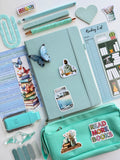 Collection of stationery items including a notebook, pens, and a pencil case on a white background.