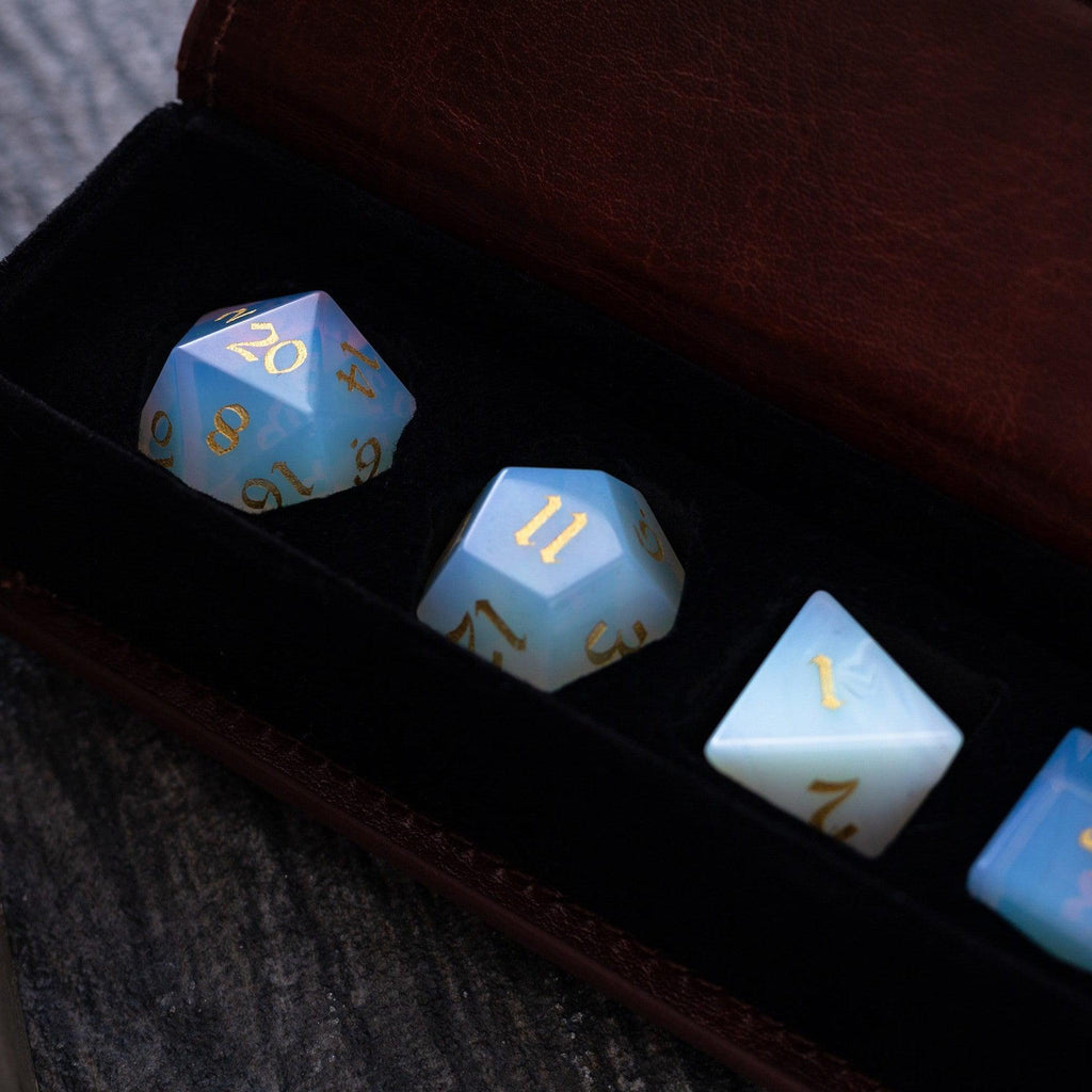 Set of glowing blue dice with gold numbers in a dark case.