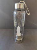 Clear water bottle with a silver base and clear crystal inside on a dark background