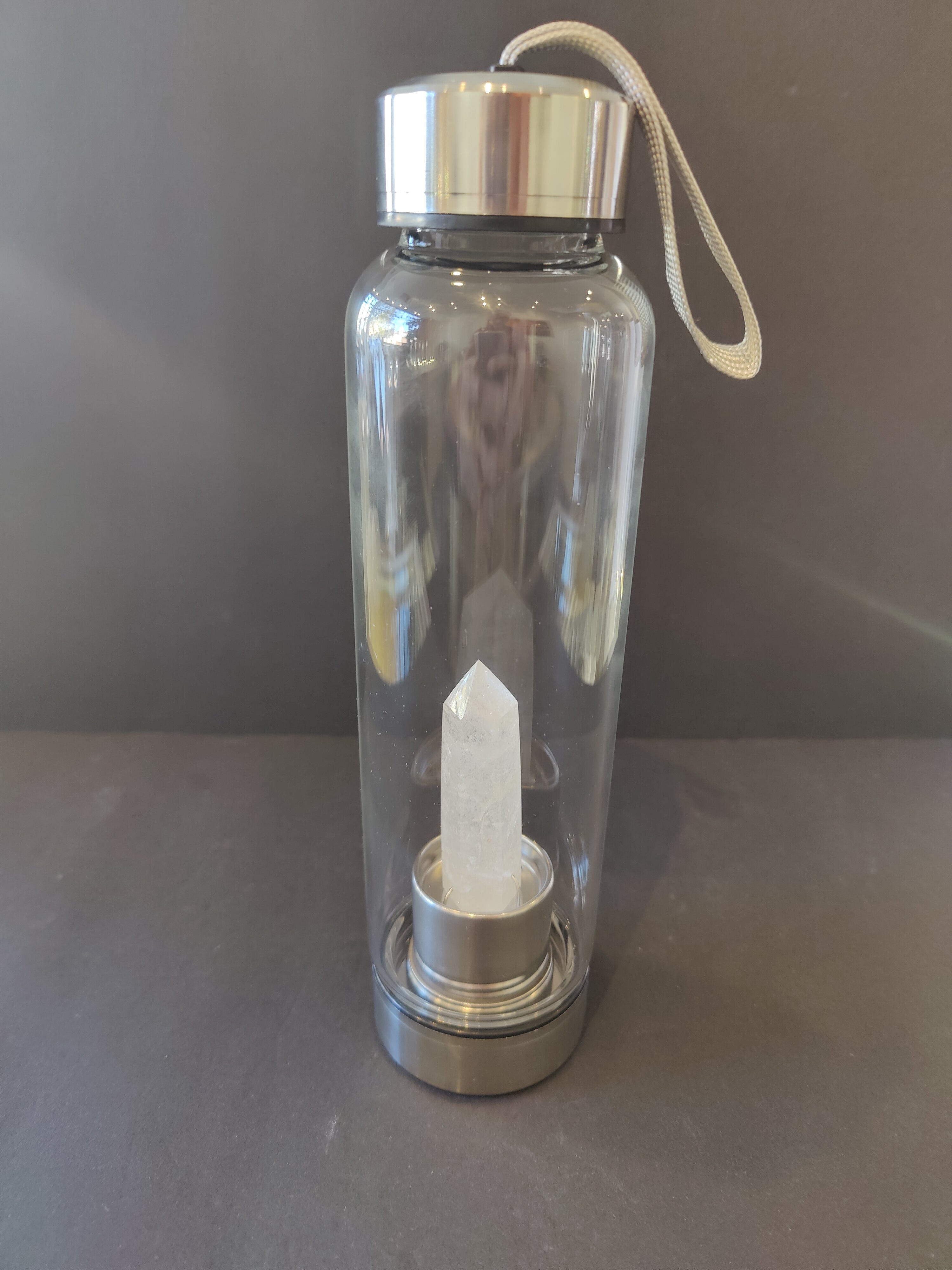 Clear water bottle with a silver base and clear crystal inside on a dark background