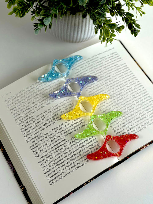 Colorful butterfly-shaped bookmarks on an open book with a plant in the background.