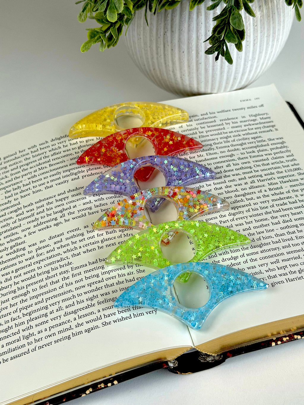 Colorful resin rings on an open book with a plant in the background