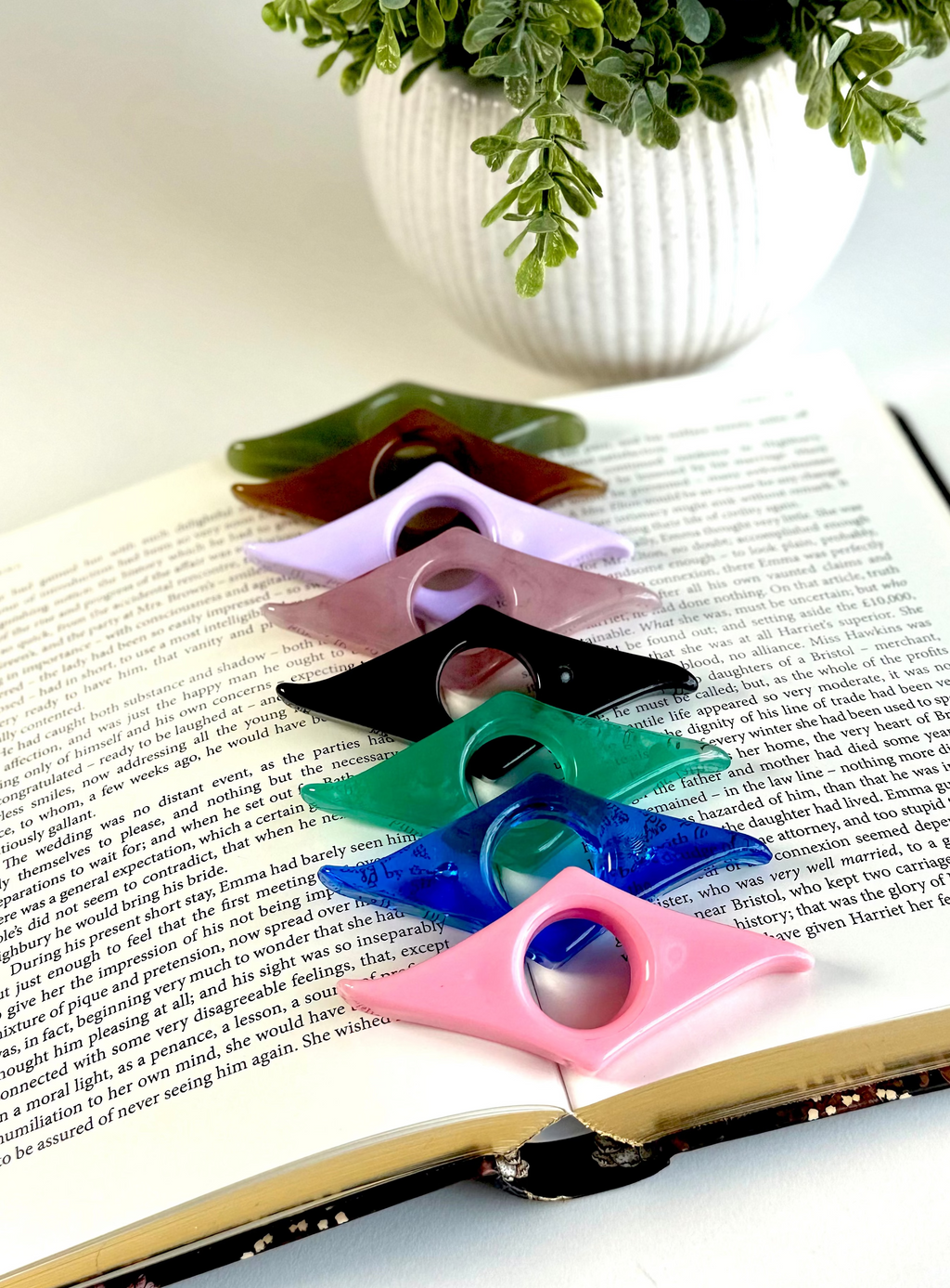Colorful plastic bookmarks on an open book with a plant in the background