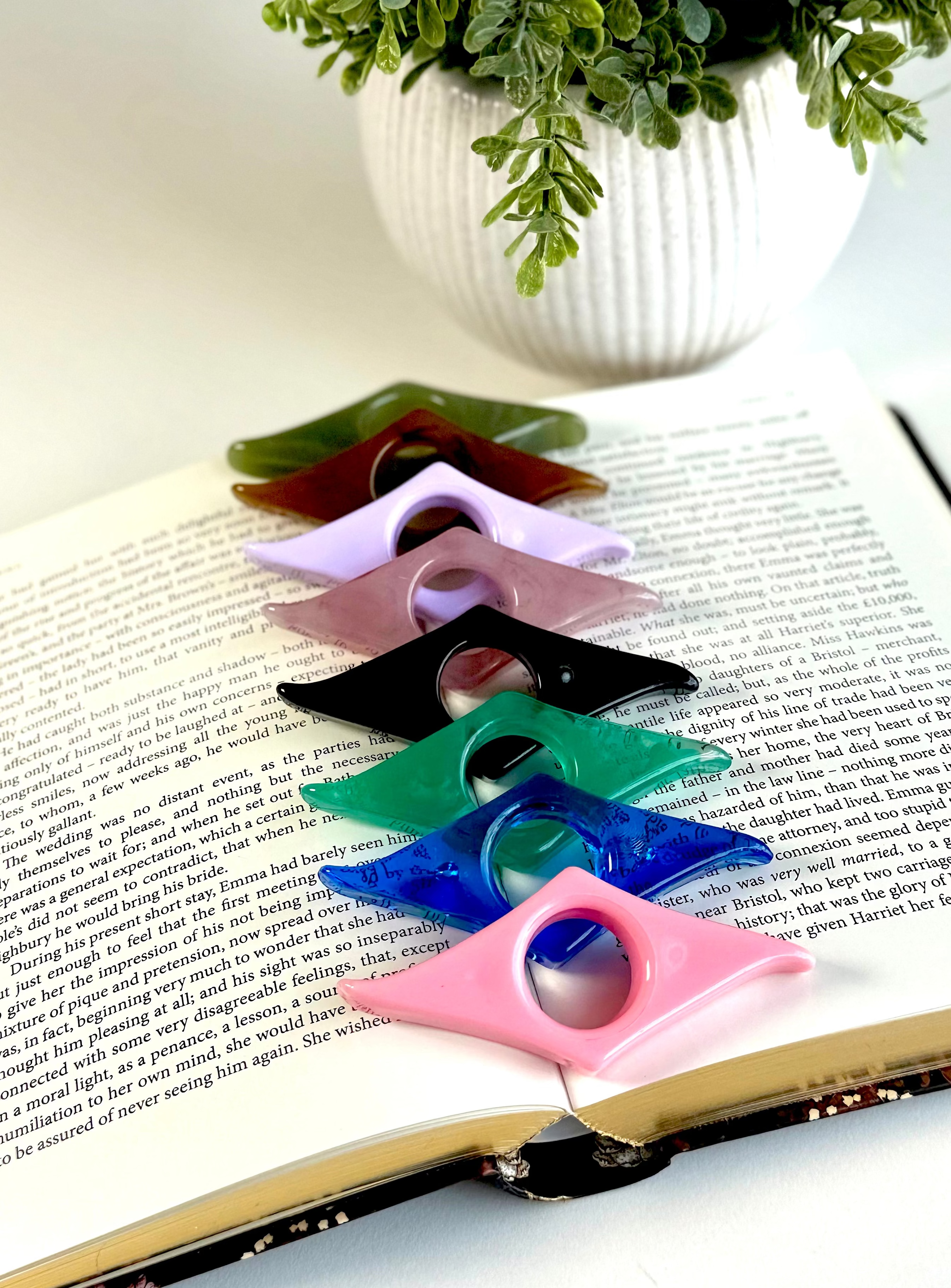 Colorful plastic bookmarks on an open book with a plant in the background