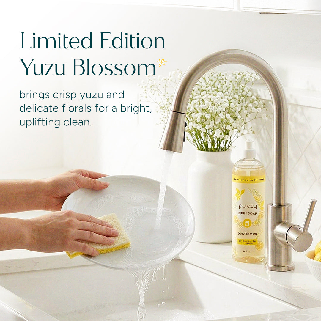 Person washing a plate with a bottle of Yuzu Blossom dish soap in a kitchen setting.