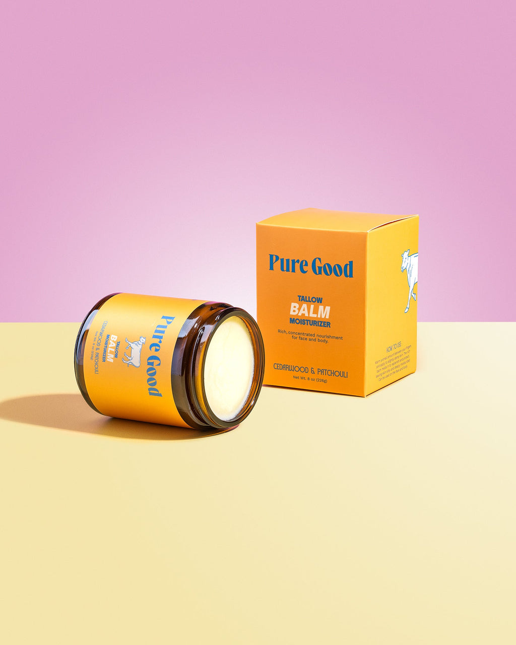 Jar of 'Pure Good' balm and its packaging on a pink and yellow gradient background