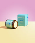 Jar of 'Pure Good' balm with a matching box on a pink and yellow gradient background