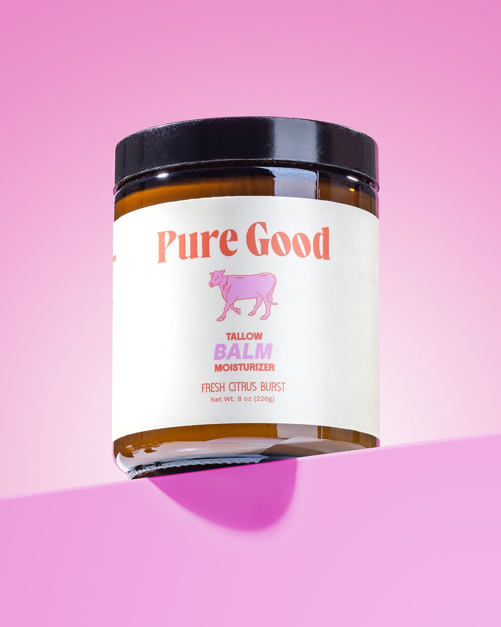 Jar of 'Pure Good' tallow balm on a pink background
