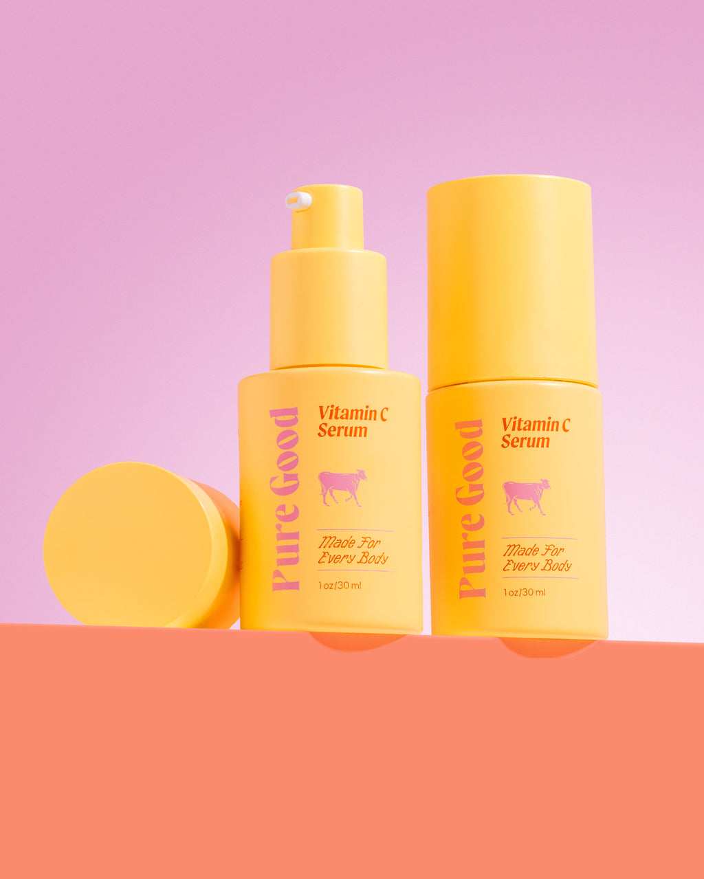 Two bottles of 'Pure Good' Vitamin C Serum on a pink and orange gradient background