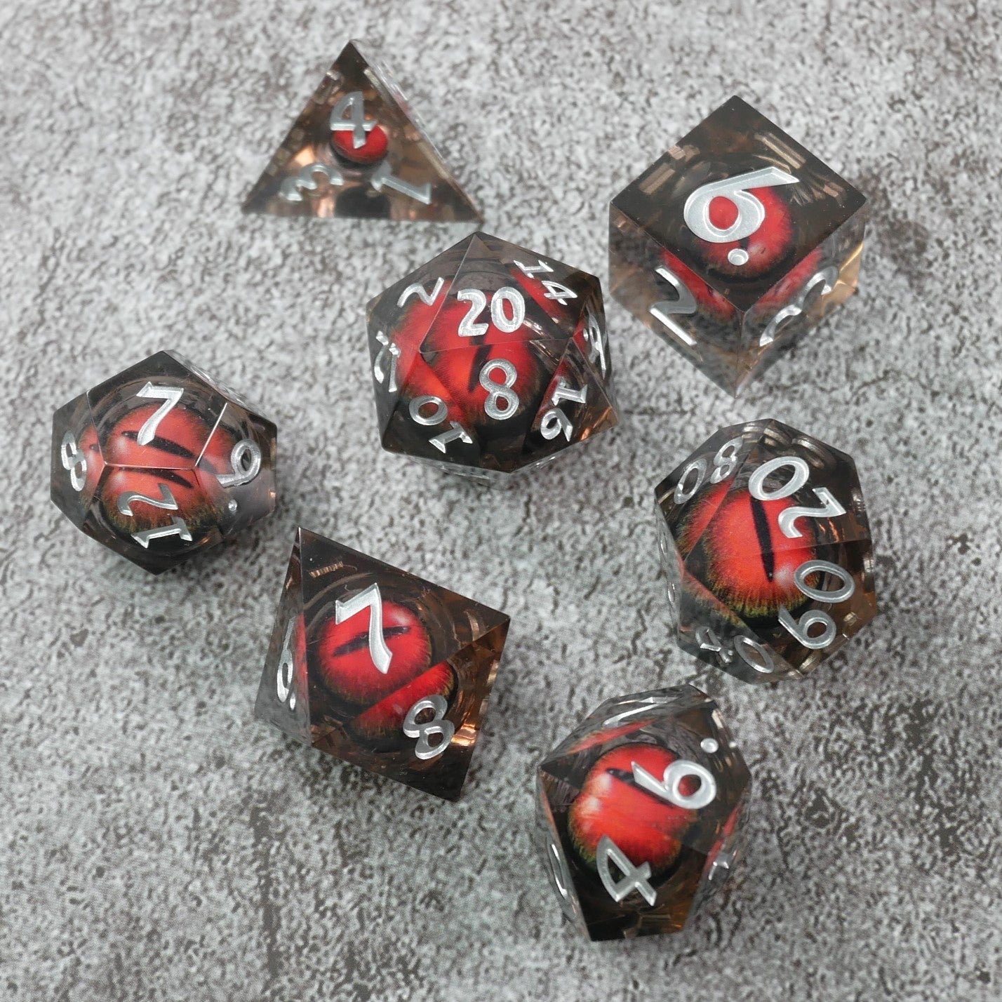 Set of polyhedral dice with red and silver numbers on a gray surface