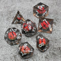 Set of polyhedral dice with red and black design on a gray surface