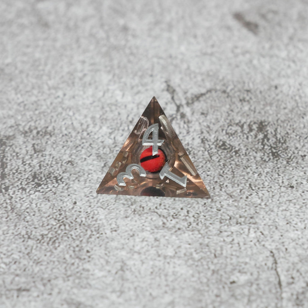 Triangular metal badge with a red and black design on a textured gray surface