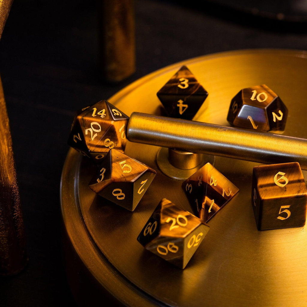 Gold polyhedral dice set on a metallic surface with a dark background