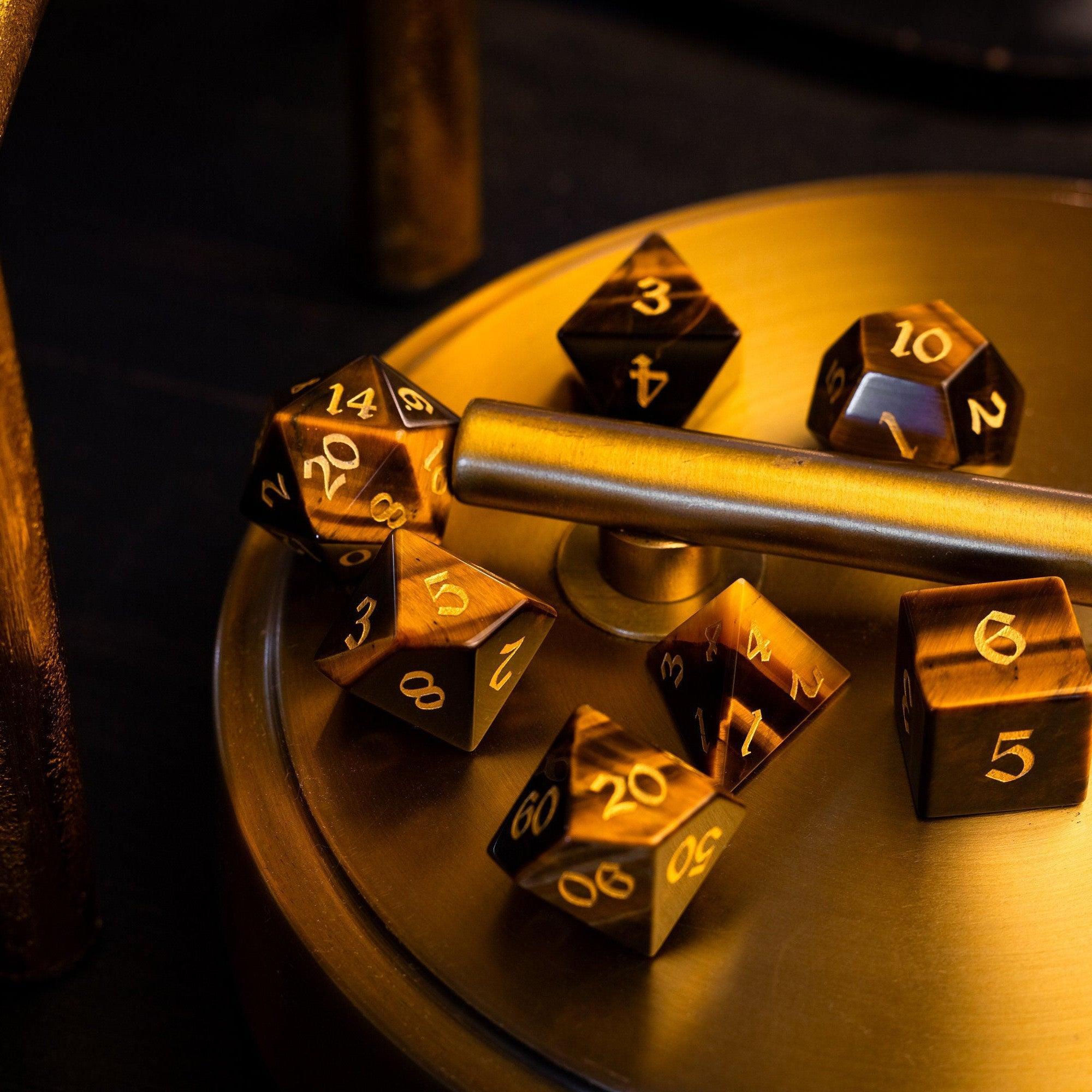 Gold polyhedral dice set on a metallic surface with a dark background