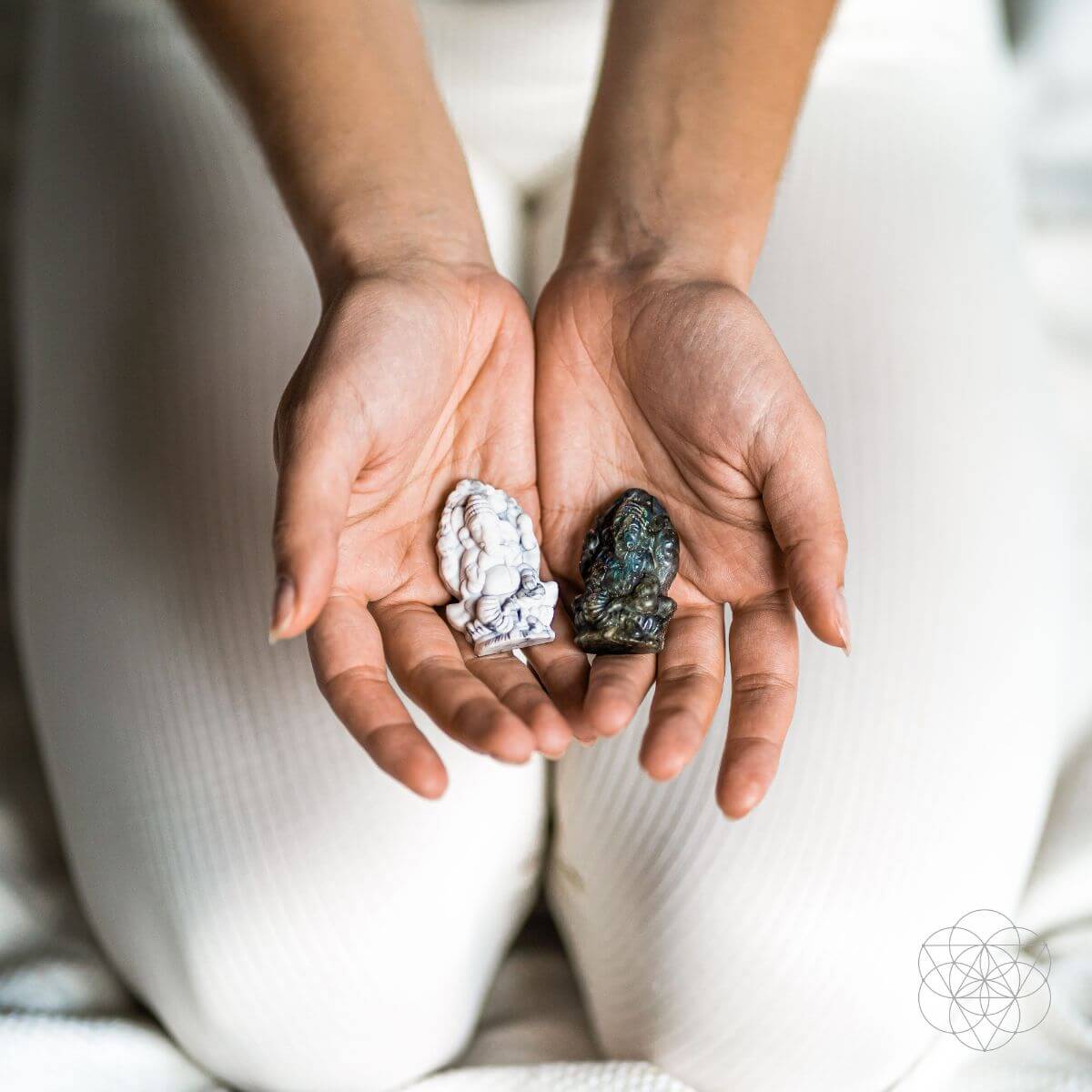 Two hands holding two different crystals against a neutral background