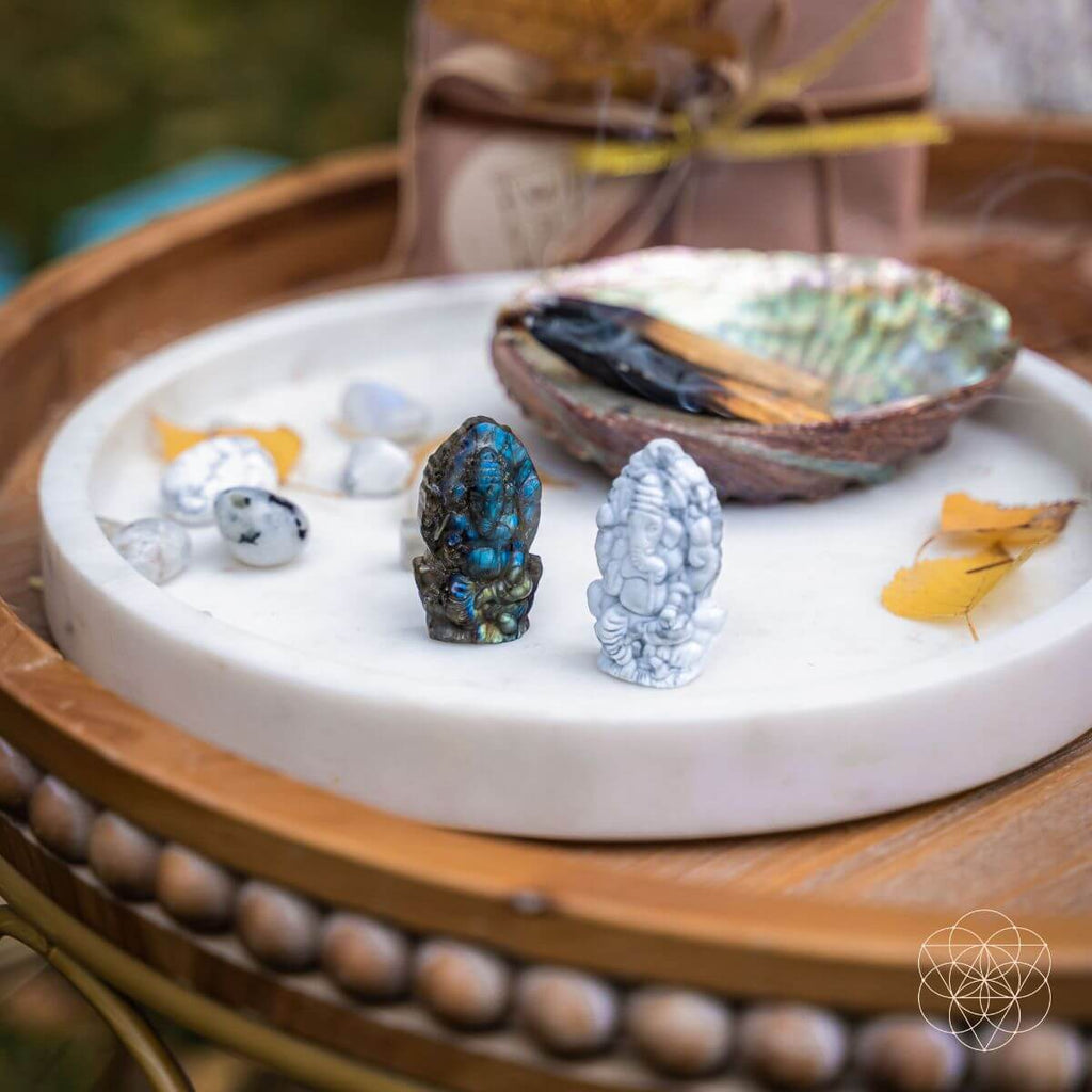 Decorative setting with stones, shells, and a small bowl on a white dish.