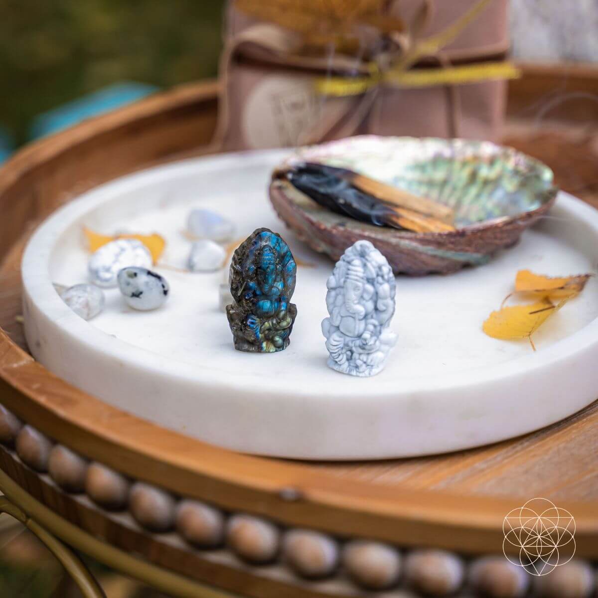 Decorative setting with stones, shells, and a small bowl on a white dish.