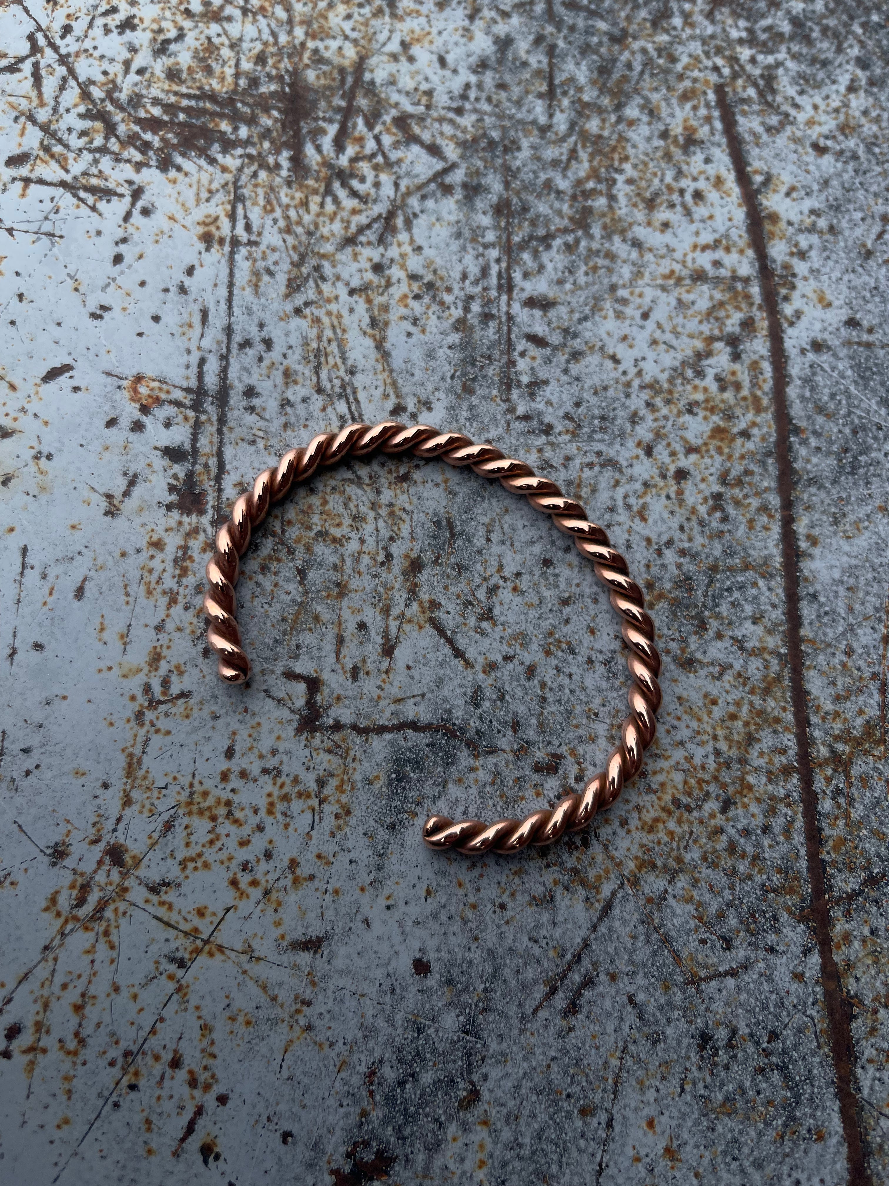 Bronze hoop earring on a textured metal surface