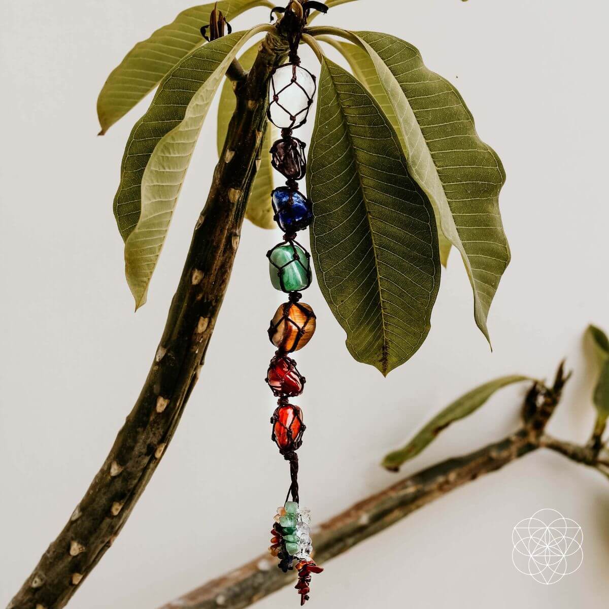 Colorful beaded hanging ornament on a branch with green leaves