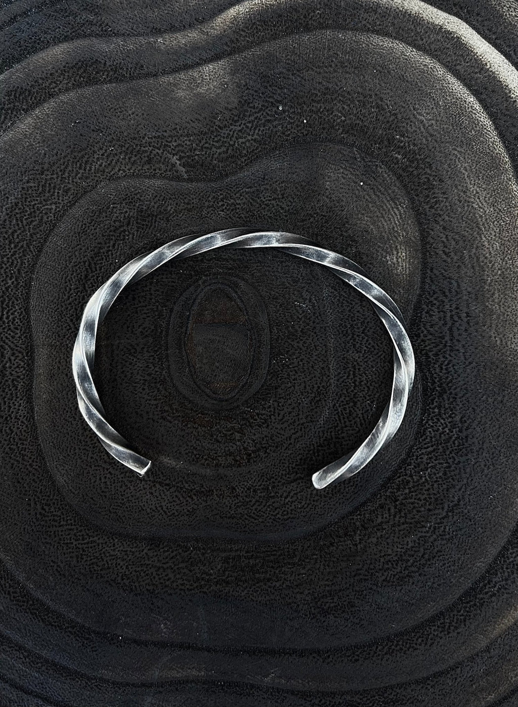 Silver bracelet on a textured black surface