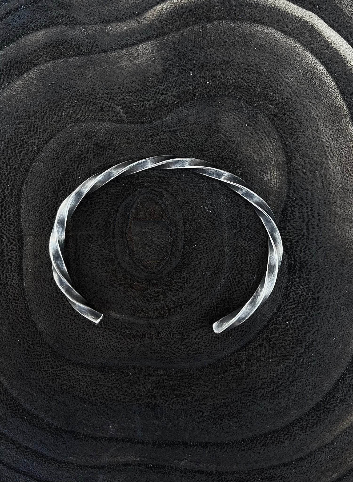 Silver bracelet on a textured black surface