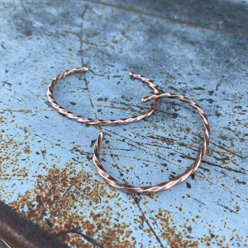 Pair of copper hoop earrings on a textured blue surface