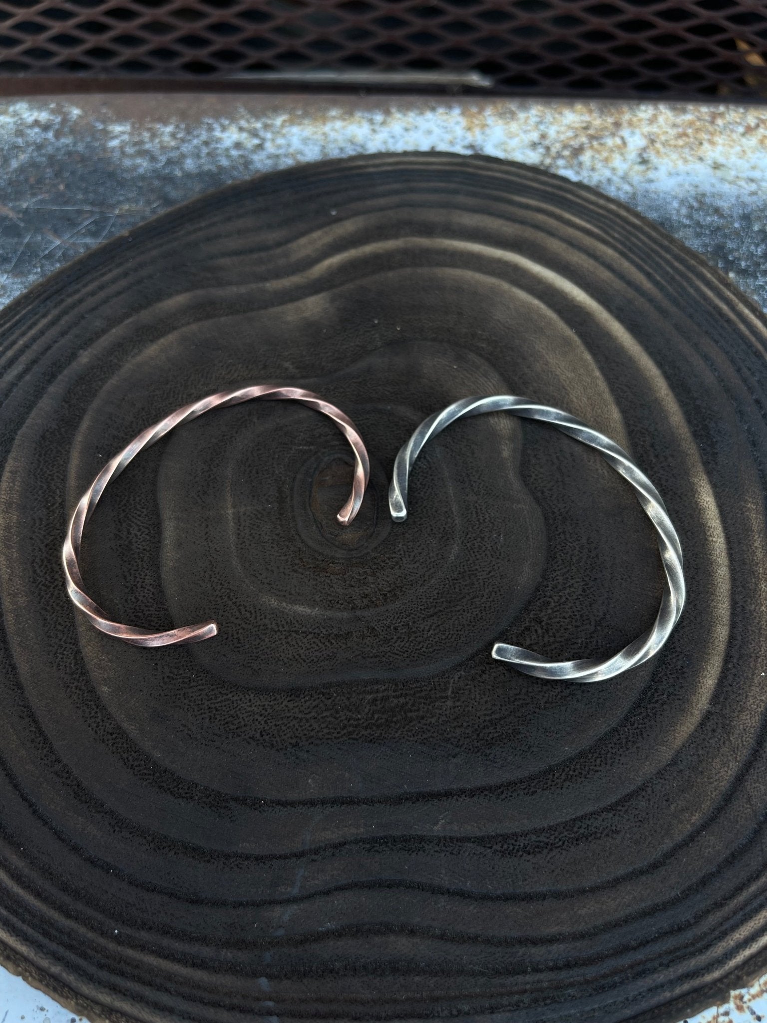 Two copper bracelets on a textured black surface